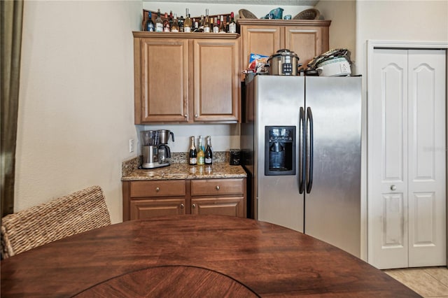 kitchen featuring dark stone countertops and stainless steel fridge with ice dispenser