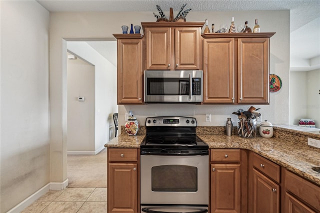 kitchen featuring stainless steel appliances, light colored carpet, and stone counters