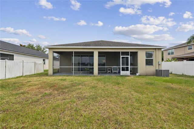 rear view of property with a sunroom, central air condition unit, and a yard