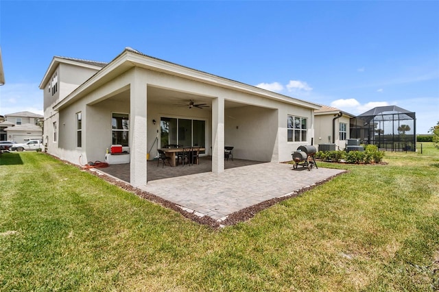 rear view of house with a yard, glass enclosure, ceiling fan, and a patio area