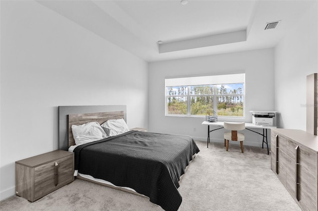 bedroom with light colored carpet and a tray ceiling