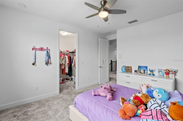 carpeted bedroom with a spacious closet, a closet, and ceiling fan