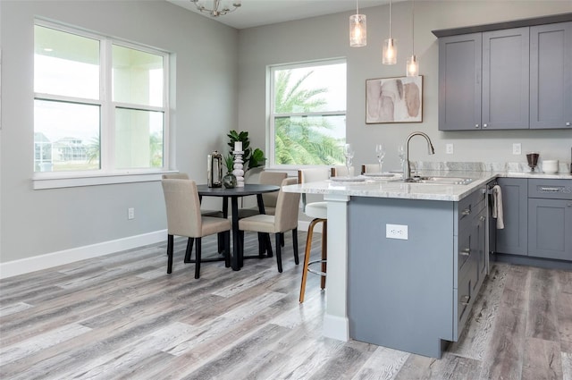 3431 Sheephead Dr, Hernando Beach, FL 34607 - kitchen with gray cabinets, light wood-style floors, a kitchen bar, a peninsula, and pendant lighting