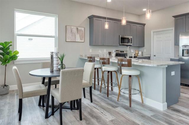 3431 Sheephead Dr, Hernando Beach, FL 34607 - kitchen featuring stainless steel appliances, gray cabinets, light wood-style flooring, a kitchen bar, and recessed lighting