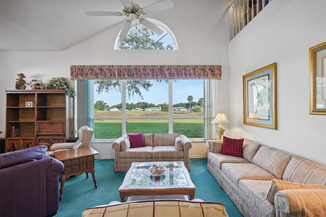 living room with ceiling fan, plenty of natural light, high vaulted ceiling, and dark colored carpet