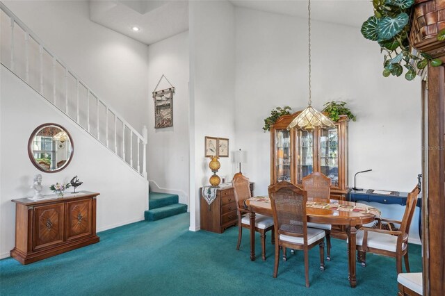 dining room featuring a towering ceiling and carpet floors