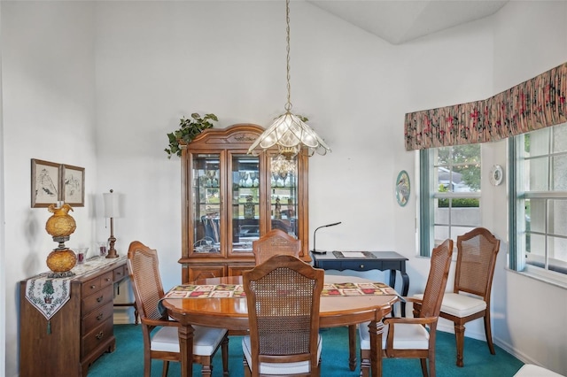 carpeted dining room with a high ceiling and an inviting chandelier