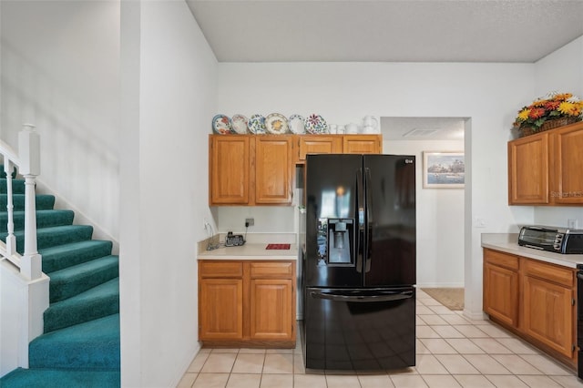 kitchen with light tile patterned floors and black fridge