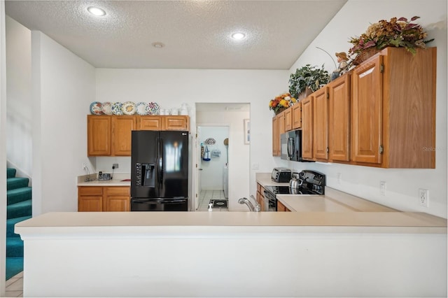 kitchen featuring kitchen peninsula, black appliances, and a textured ceiling