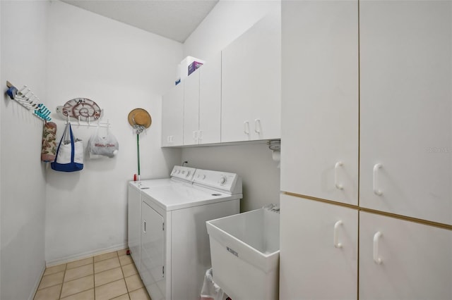 laundry room featuring separate washer and dryer, sink, light tile patterned floors, and cabinets