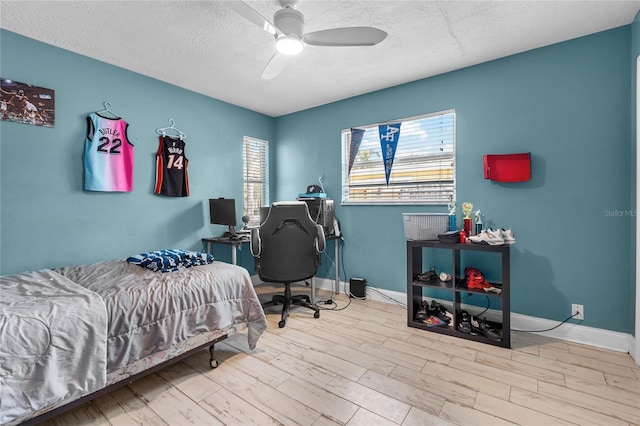 bedroom with ceiling fan, light hardwood / wood-style floors, and a textured ceiling