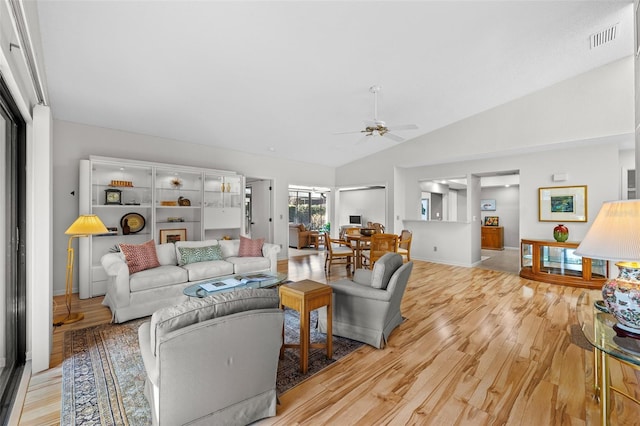 living room featuring ceiling fan, vaulted ceiling, and light wood-type flooring