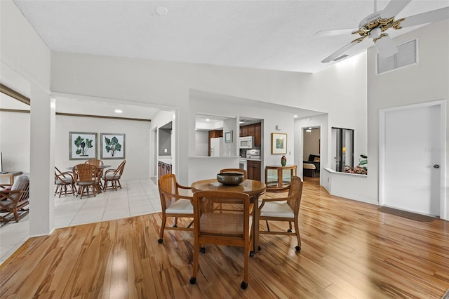 dining area featuring ceiling fan, light hardwood / wood-style floors, and lofted ceiling