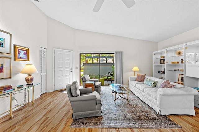 living room with ceiling fan, vaulted ceiling, and light hardwood / wood-style flooring