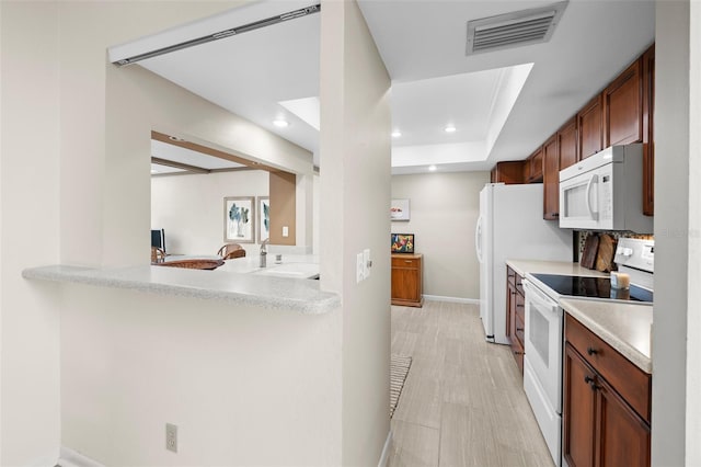 kitchen with kitchen peninsula, light wood-type flooring, white appliances, and sink