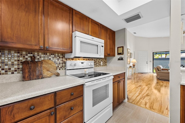 kitchen featuring decorative backsplash, light hardwood / wood-style flooring, and white appliances