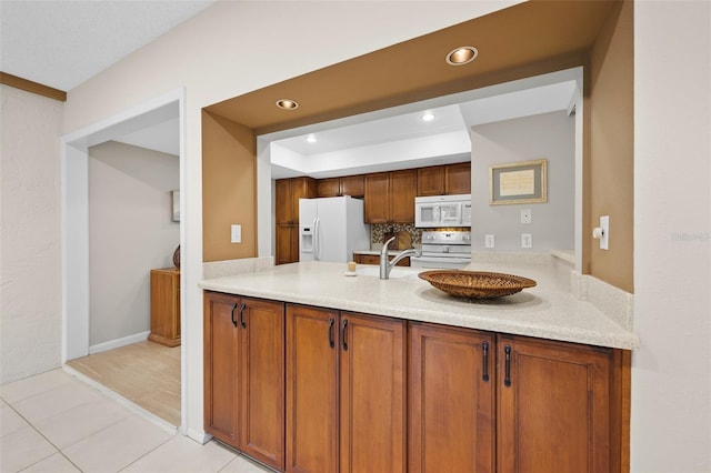 kitchen with backsplash, sink, light tile patterned floors, and white appliances