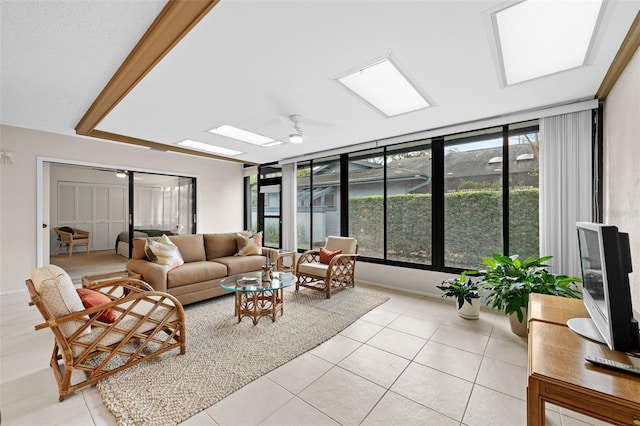 tiled living room with ceiling fan and a skylight