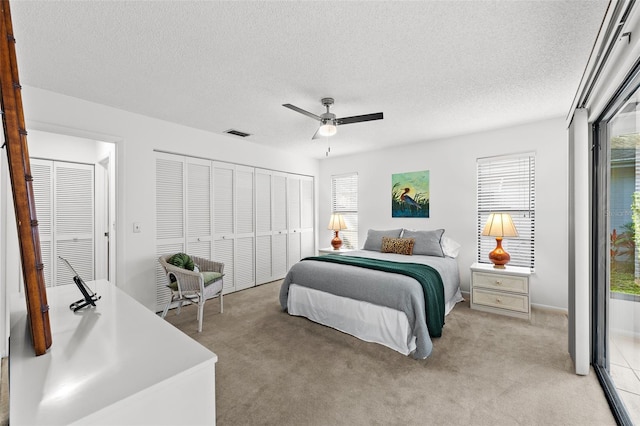 carpeted bedroom with ceiling fan and a textured ceiling