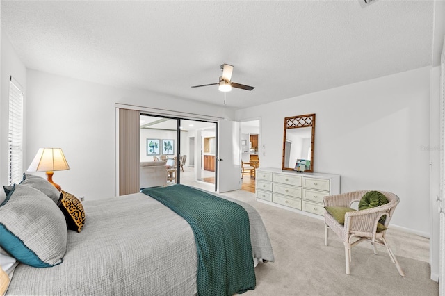 bedroom featuring ceiling fan, access to exterior, light colored carpet, and a textured ceiling