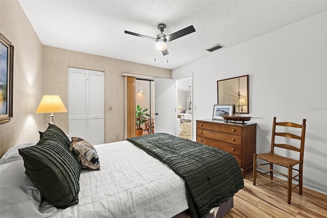 bedroom with a textured ceiling, light hardwood / wood-style floors, and ceiling fan