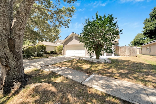 view of property hidden behind natural elements featuring a front lawn and a garage