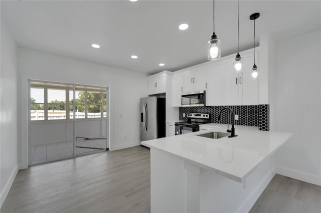 kitchen featuring pendant lighting, sink, appliances with stainless steel finishes, light hardwood / wood-style floors, and white cabinetry