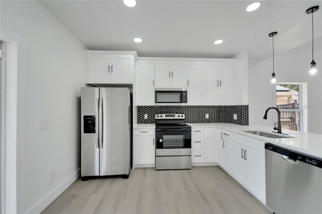 kitchen featuring sink, decorative light fixtures, light hardwood / wood-style floors, white cabinetry, and stainless steel appliances