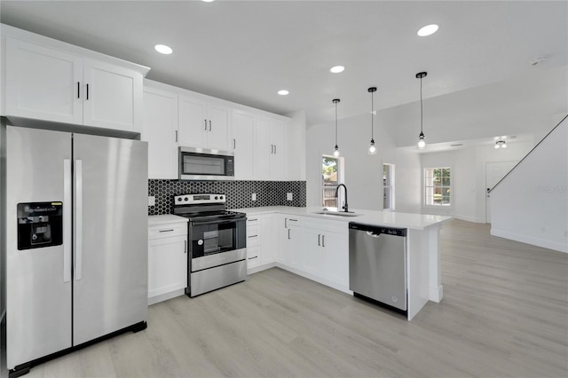 kitchen with white cabinetry, stainless steel appliances, kitchen peninsula, pendant lighting, and light hardwood / wood-style floors