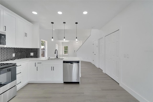 kitchen with white cabinets, sink, hanging light fixtures, light hardwood / wood-style floors, and stainless steel appliances