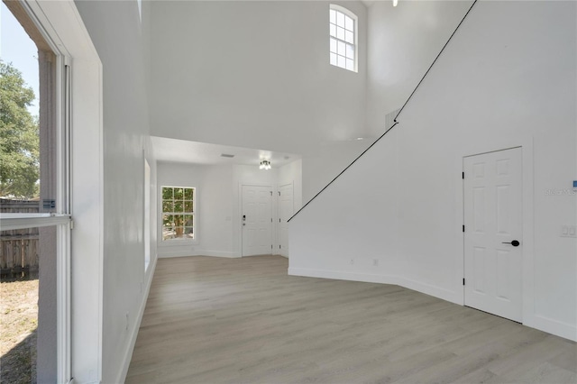 unfurnished living room with a high ceiling, light hardwood / wood-style floors, and a wealth of natural light