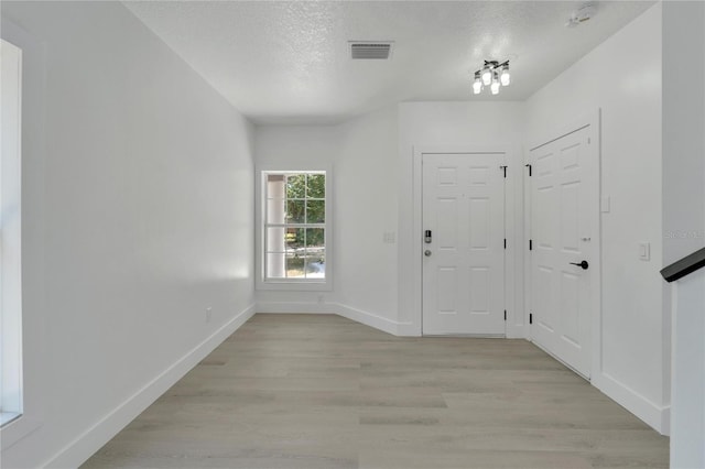 foyer entrance with a textured ceiling and light hardwood / wood-style flooring