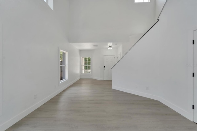 unfurnished living room featuring a towering ceiling and light wood-type flooring