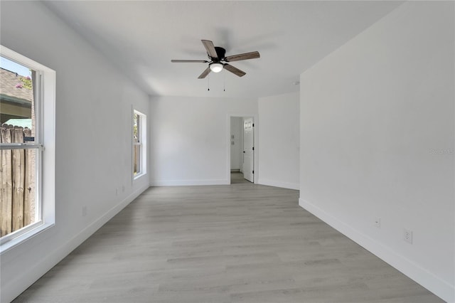 spare room featuring ceiling fan, a healthy amount of sunlight, and light wood-type flooring