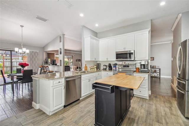 kitchen featuring white cabinetry, sink, hanging light fixtures, stainless steel appliances, and kitchen peninsula