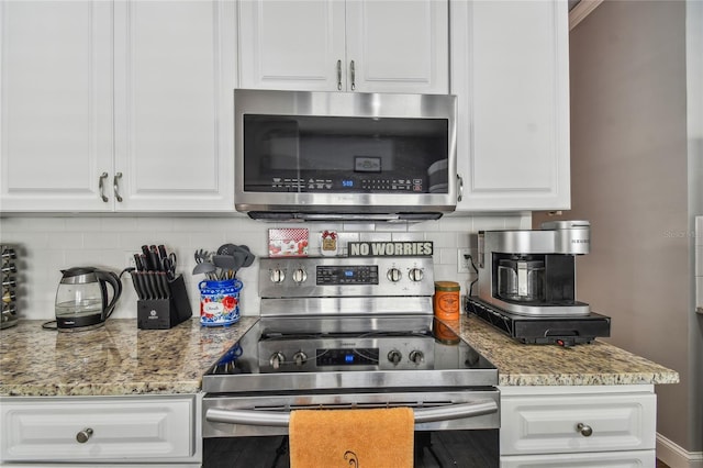 kitchen with tasteful backsplash, white cabinets, and stainless steel appliances