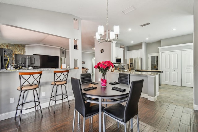 dining area featuring a notable chandelier, sink, and vaulted ceiling