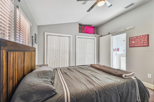 bedroom featuring ceiling fan, two closets, and vaulted ceiling