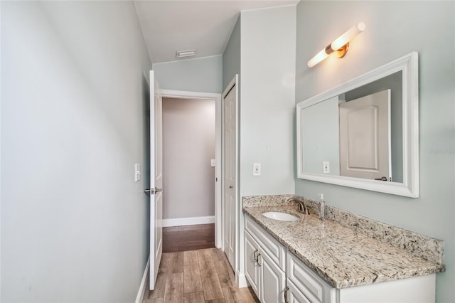 bathroom featuring vanity, wood-type flooring, and vaulted ceiling