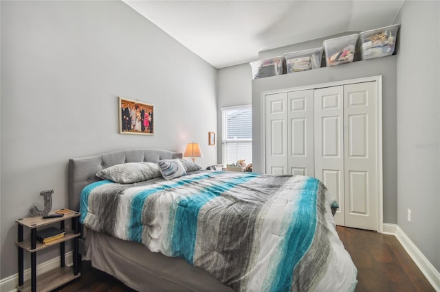 bedroom with dark hardwood / wood-style floors, a closet, and lofted ceiling