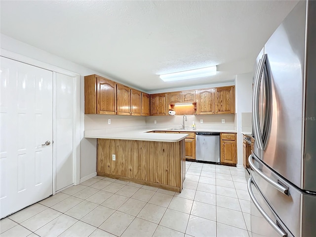 kitchen featuring kitchen peninsula, sink, light tile patterned floors, and appliances with stainless steel finishes