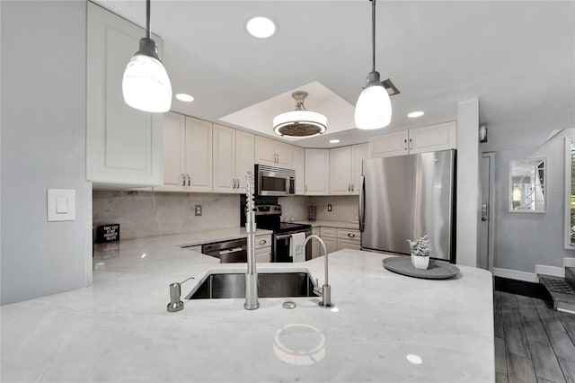 kitchen with backsplash, sink, stainless steel appliances, and decorative light fixtures