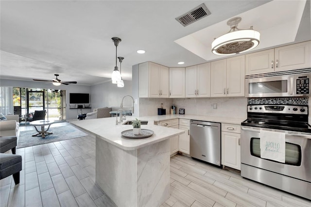 kitchen featuring ceiling fan, sink, stainless steel appliances, kitchen peninsula, and decorative light fixtures