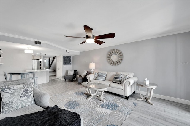 living room with light wood-type flooring, ceiling fan, and ornamental molding