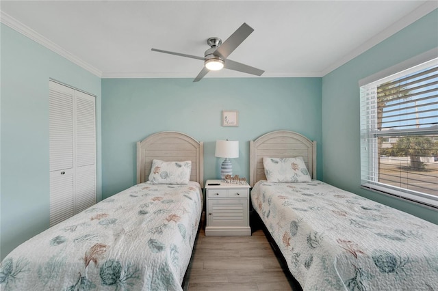 bedroom featuring ceiling fan, ornamental molding, light hardwood / wood-style flooring, and a closet