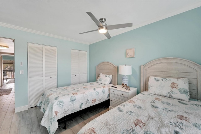 bedroom with hardwood / wood-style floors, ceiling fan, crown molding, and two closets