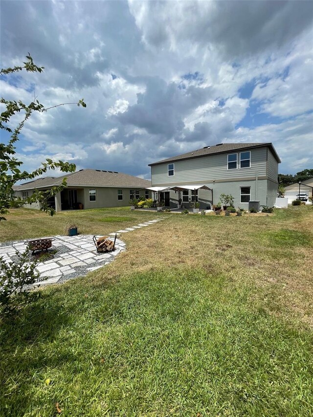 back of property with a yard and an outdoor fire pit