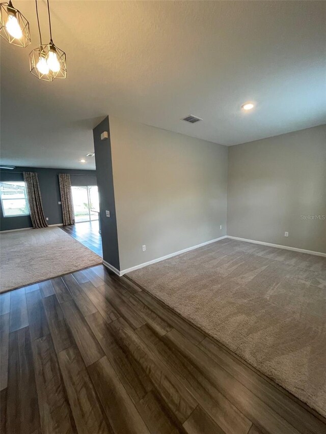 empty room with dark hardwood / wood-style floors and plenty of natural light