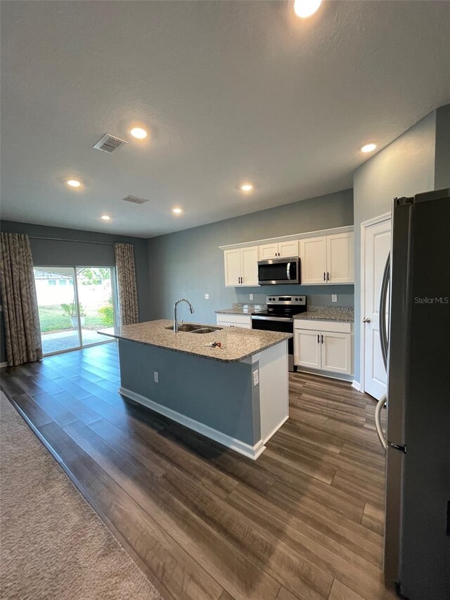 kitchen featuring dark wood-type flooring, a center island with sink, white cabinets, sink, and stainless steel appliances