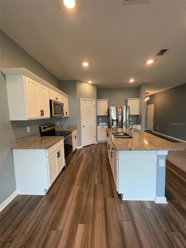 kitchen featuring appliances with stainless steel finishes, dark hardwood / wood-style flooring, white cabinetry, and an island with sink